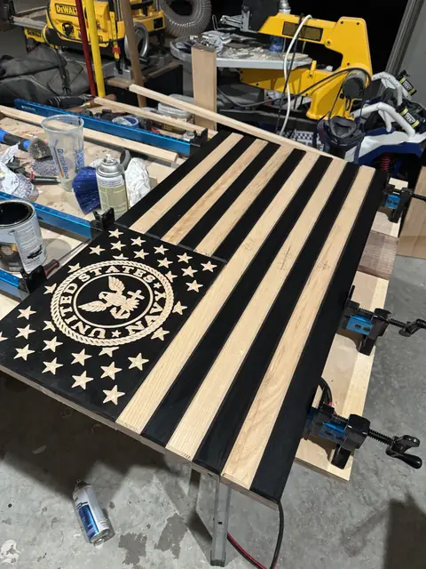 U.S. Navy flag on the bench: Black and natural hardwood stripes with a carved Navy seal, clamped up mid-build.
