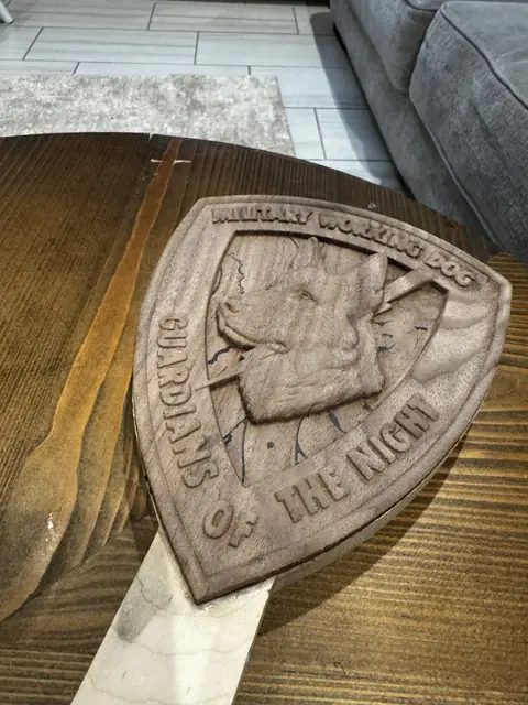 Guardians of the Night paddle: Close-up of a carved Military Working Dog shield in walnut.